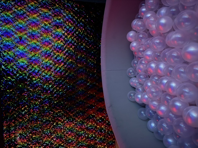 A colourful light-up ball pit against a sparkling rainbow wall at The Little Borough
